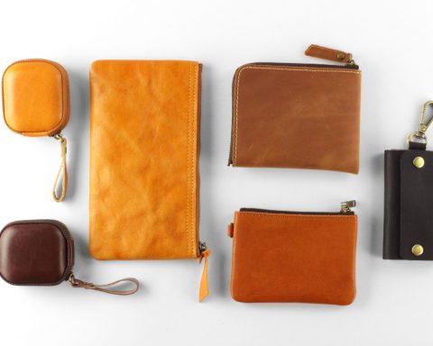 An assortment of leather pouches and wallets, ranging in color from light brown to almost black, against a white background.