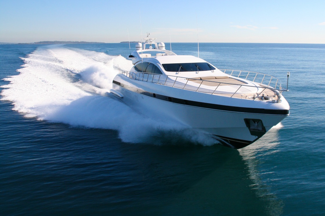 A large white yacht with black accents moves across the body of water with no other boats around it.